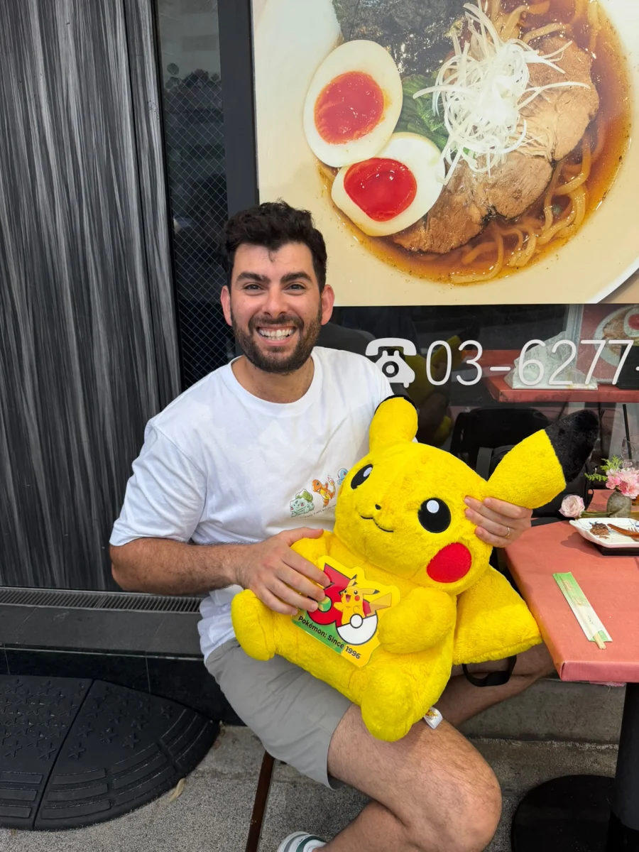 השותף שמאחורי פוקימוני השותף מחייך ומחזיק בובת פיקאצ׳ו